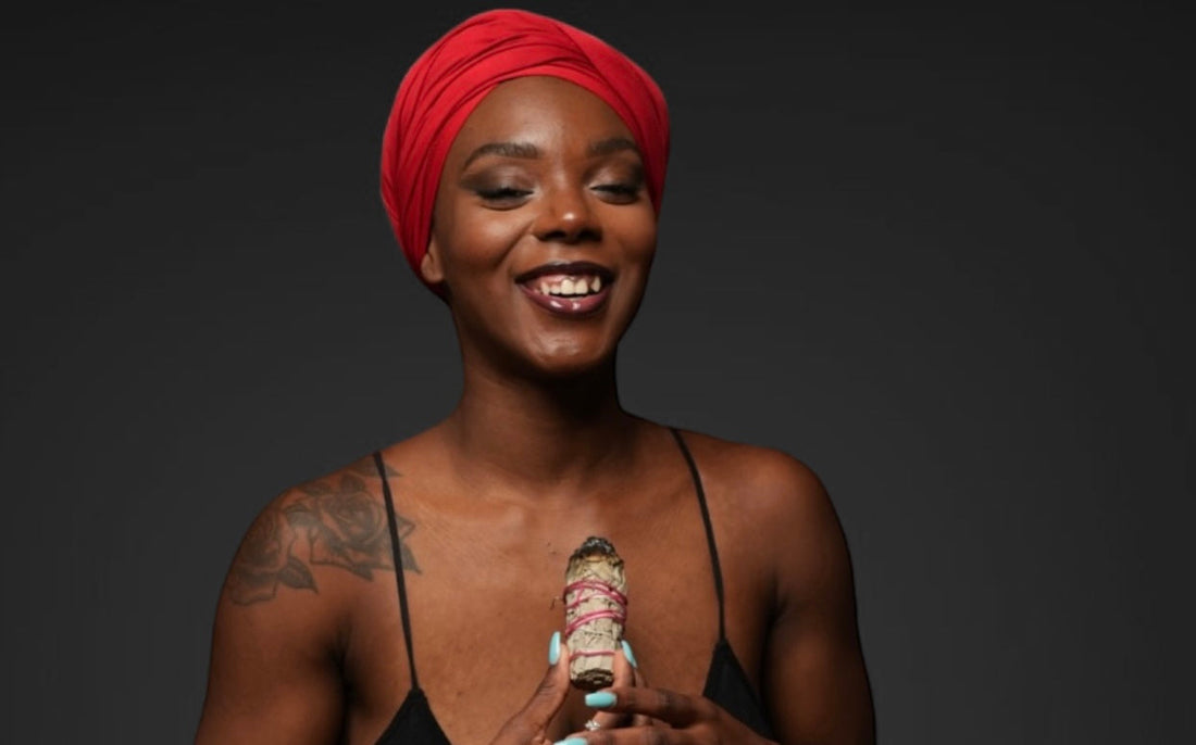 A joyful woman sits cross-legged on the floor, surrounded by colorful flowers. She holds a smudge stick, exuding a sense of peace and mindfulness. The vibrant colors highlight themes of meditation, wellness, and spirituality.